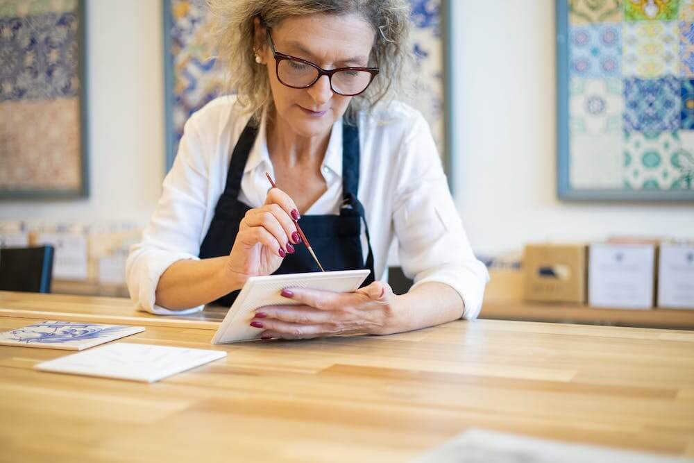 A senior woman is using a tablet at a table, engaging in social activities.